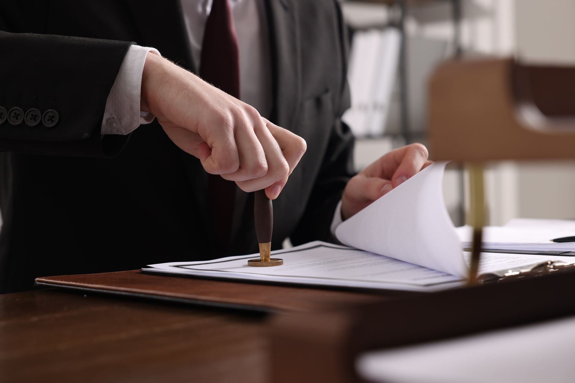 A notary in a suit and tie is stamping a document on a clipboard.