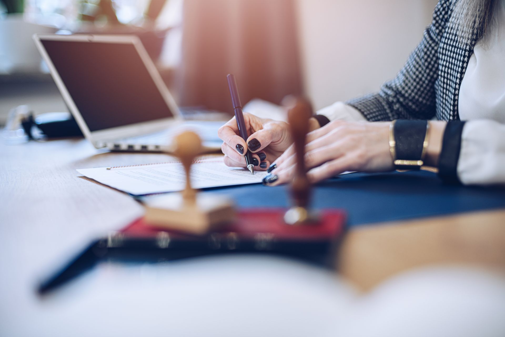 A notary public woman is sitting at a desk writing on a document.