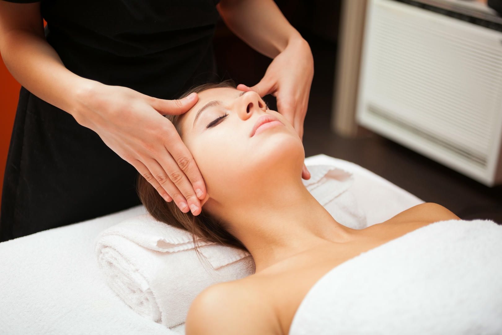 A woman is getting a facial massage at a spa
