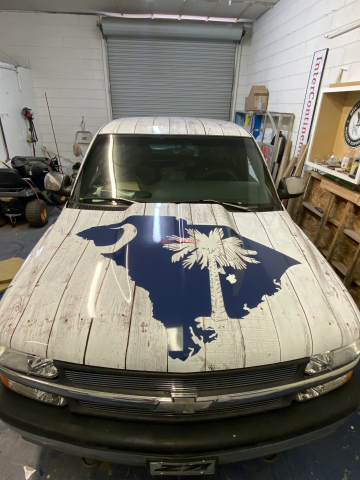 White SUV in a garage with a large blue maple leaf graphic on the hood.