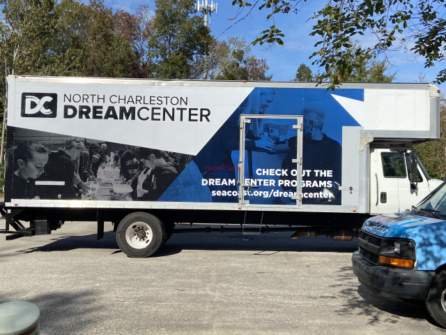 North Charleston Dream Center outreach trailer parked outdoors, white and blue with logo and contact info.