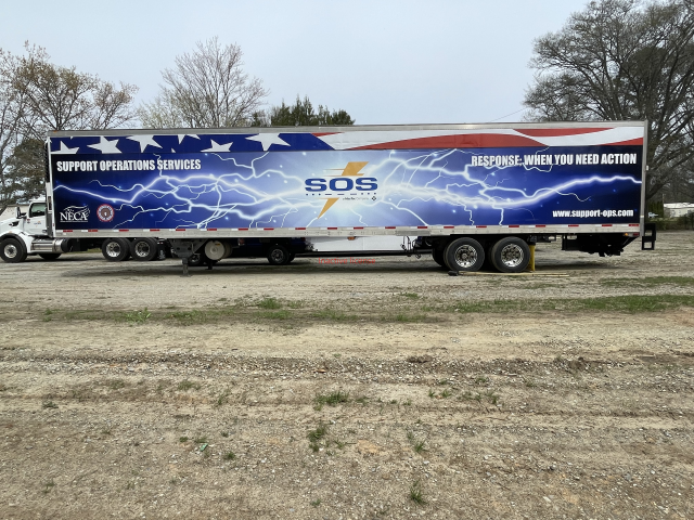 Blue SOS emergency response trailer parked on a dirt lot under cloudy skies