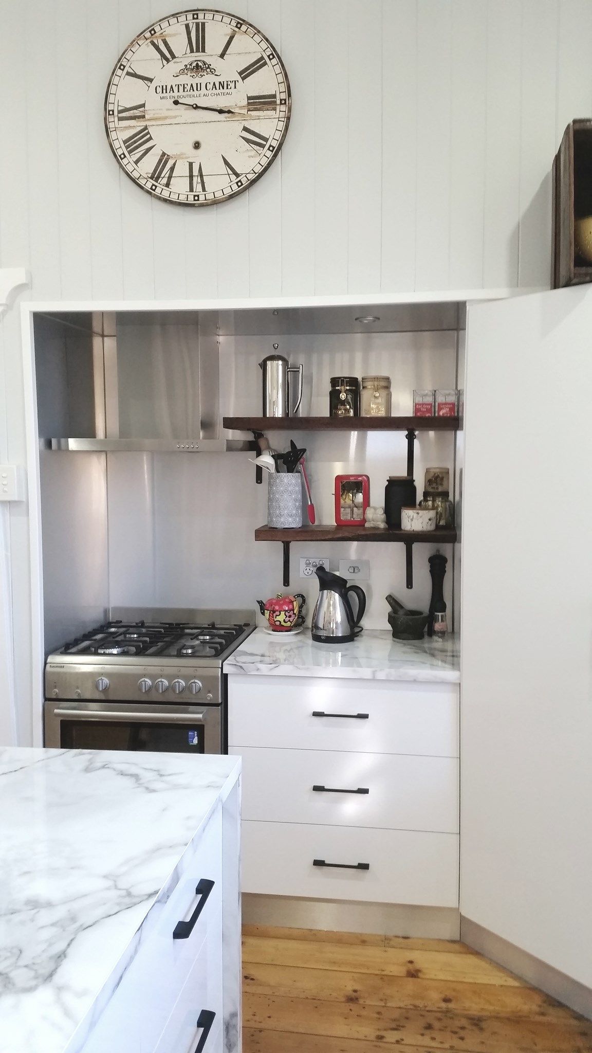 Kitchen Nook With Stove, Shelves, and a Marble Countertop, Topped With a Clock  — Payton Kitchens In Wilsonton, QLD