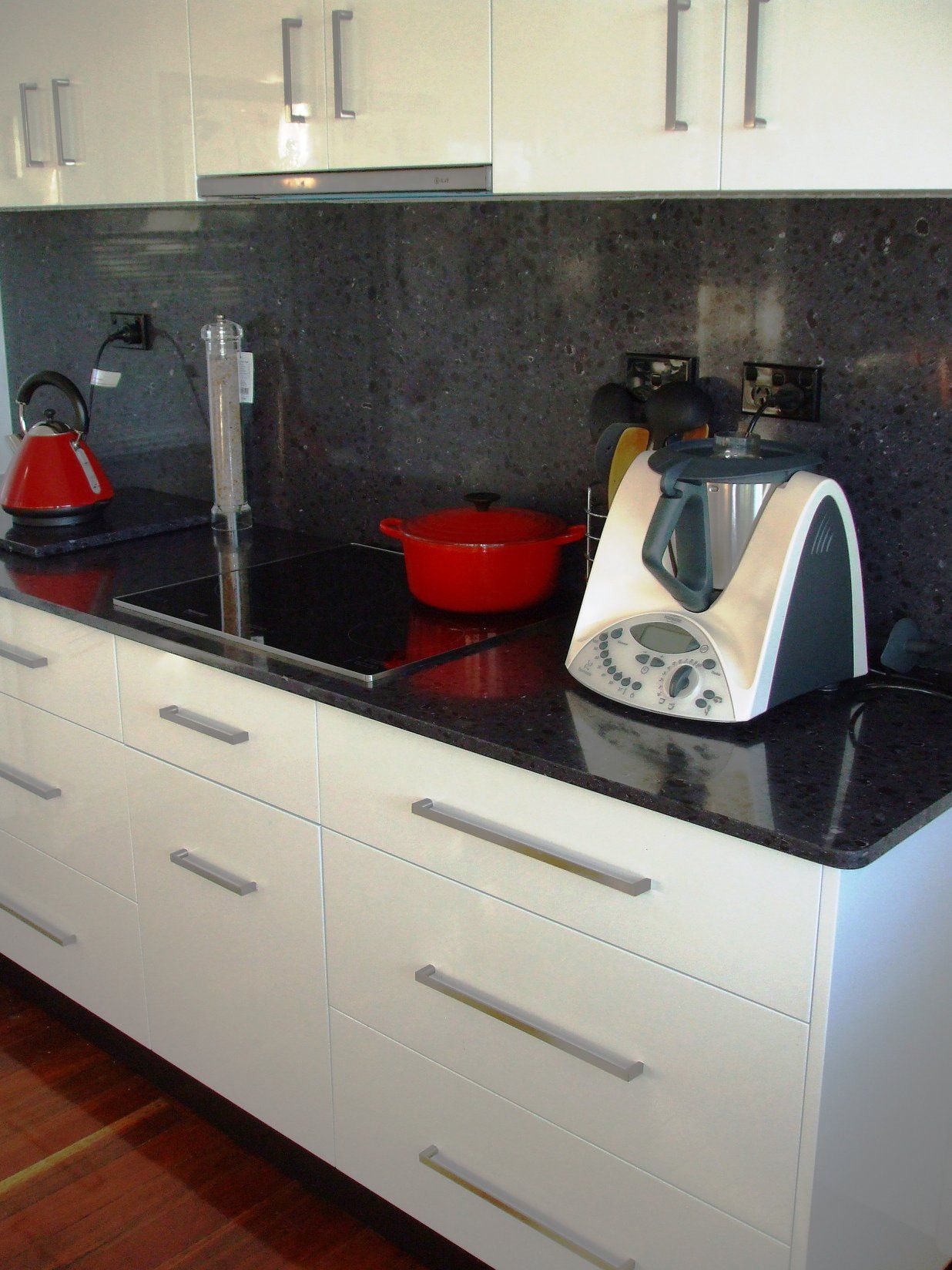 Modern White Kitchen With Black Countertop, Appliances, and Red Pot — Payton Kitchens in Pittsworth, QLD