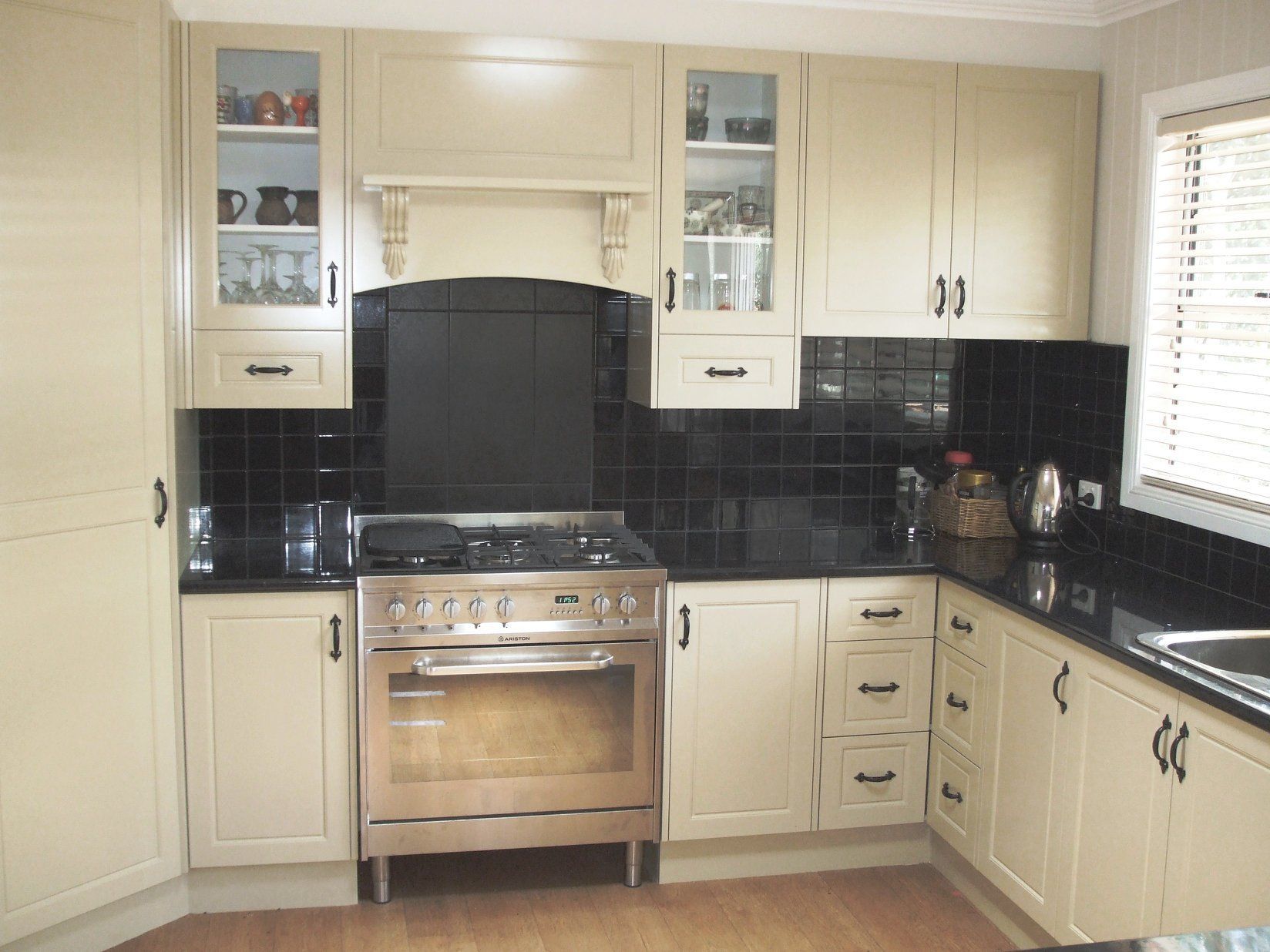 Beige Kitchen Cabinets Surround a Stainless Steel Oven and Black Countertops — Payton Kitchens in Texas, QLD