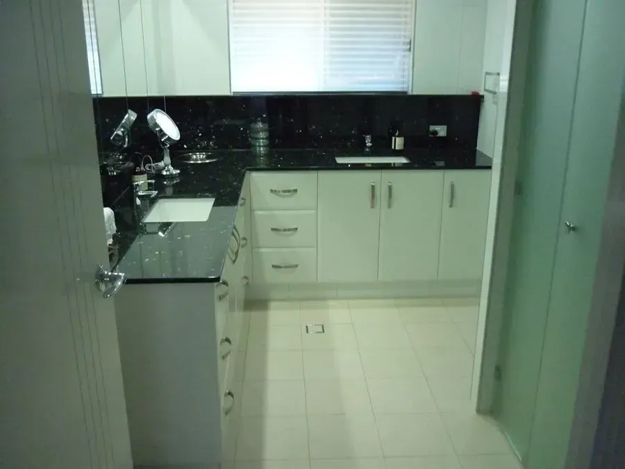 Bathroom With White Cabinets, Black Countertop, Sink, and Window With Blinds  — Payton Kitchens In Wilsonton, QLD