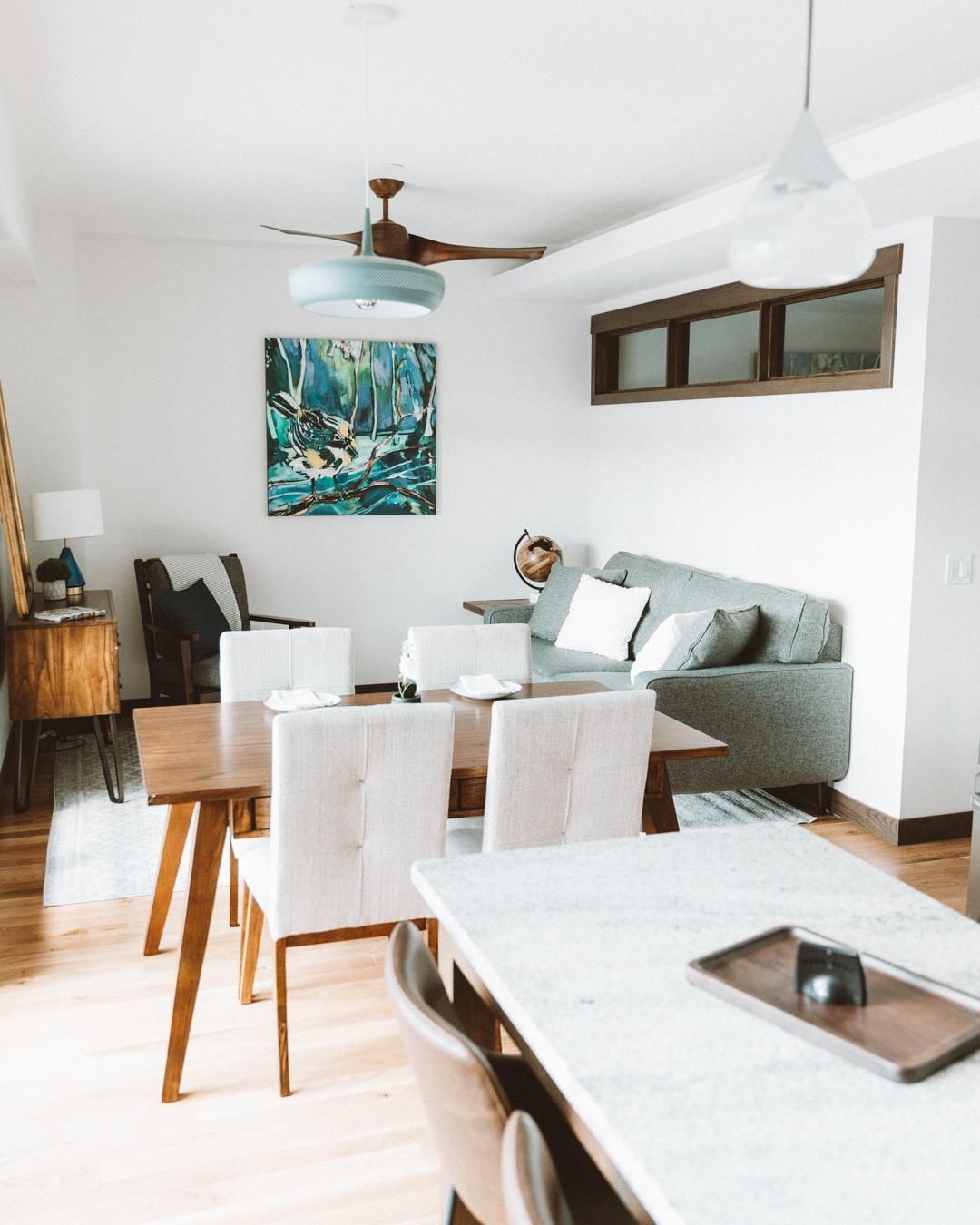 A living room with a couch , table , chairs and a ceiling fan.