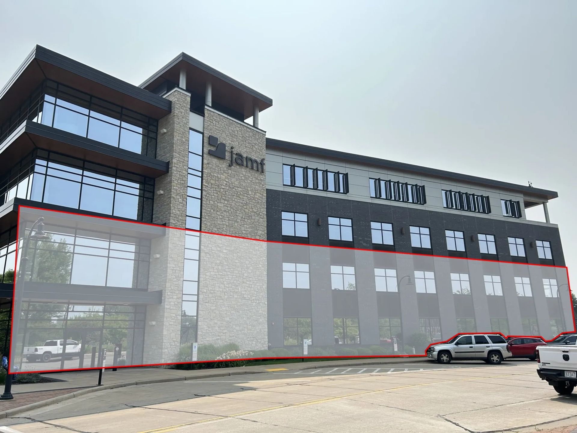 Modern office building with glass windows, gray facade, and a sign that reads