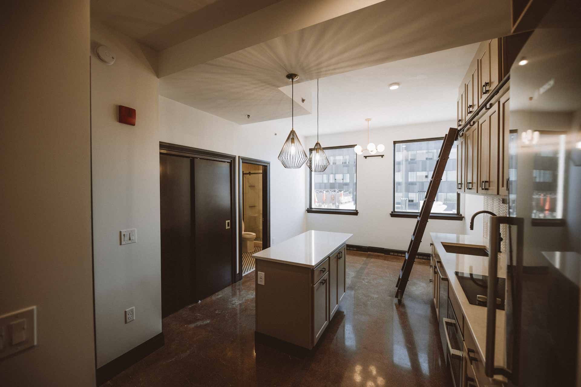 A kitchen with a large island and a ladder leading up to it.