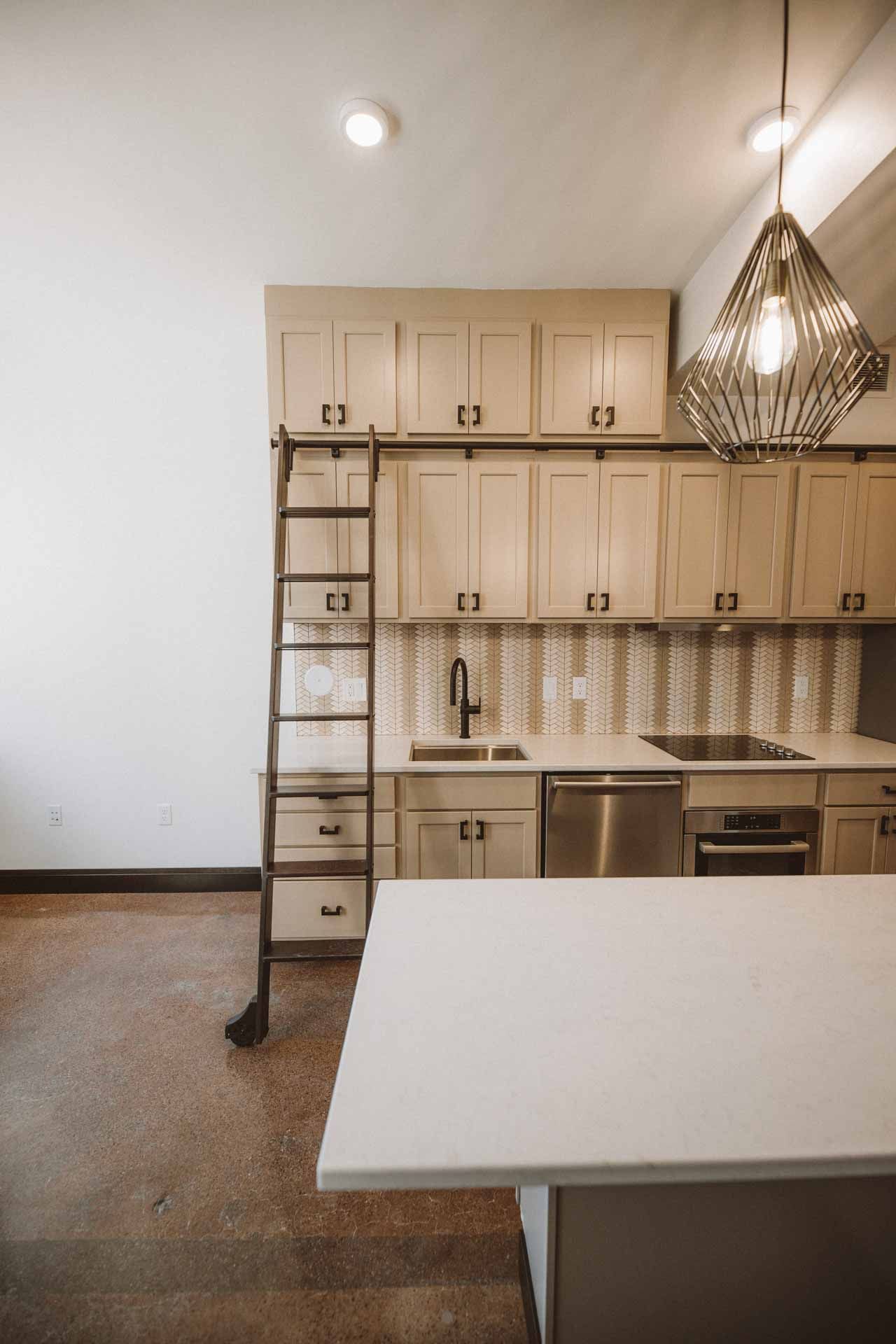 A kitchen with a ladder leading up to the sink.