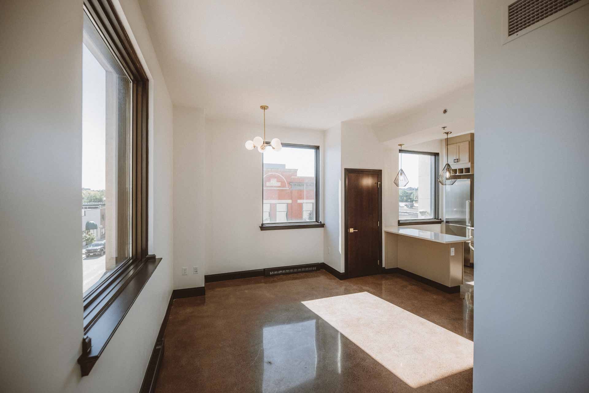 An empty living room with a lot of windows and a brown floor.
