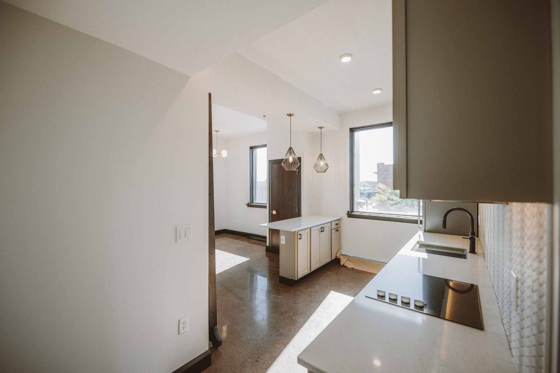 A kitchen with a stove , sink , cabinets and a window.