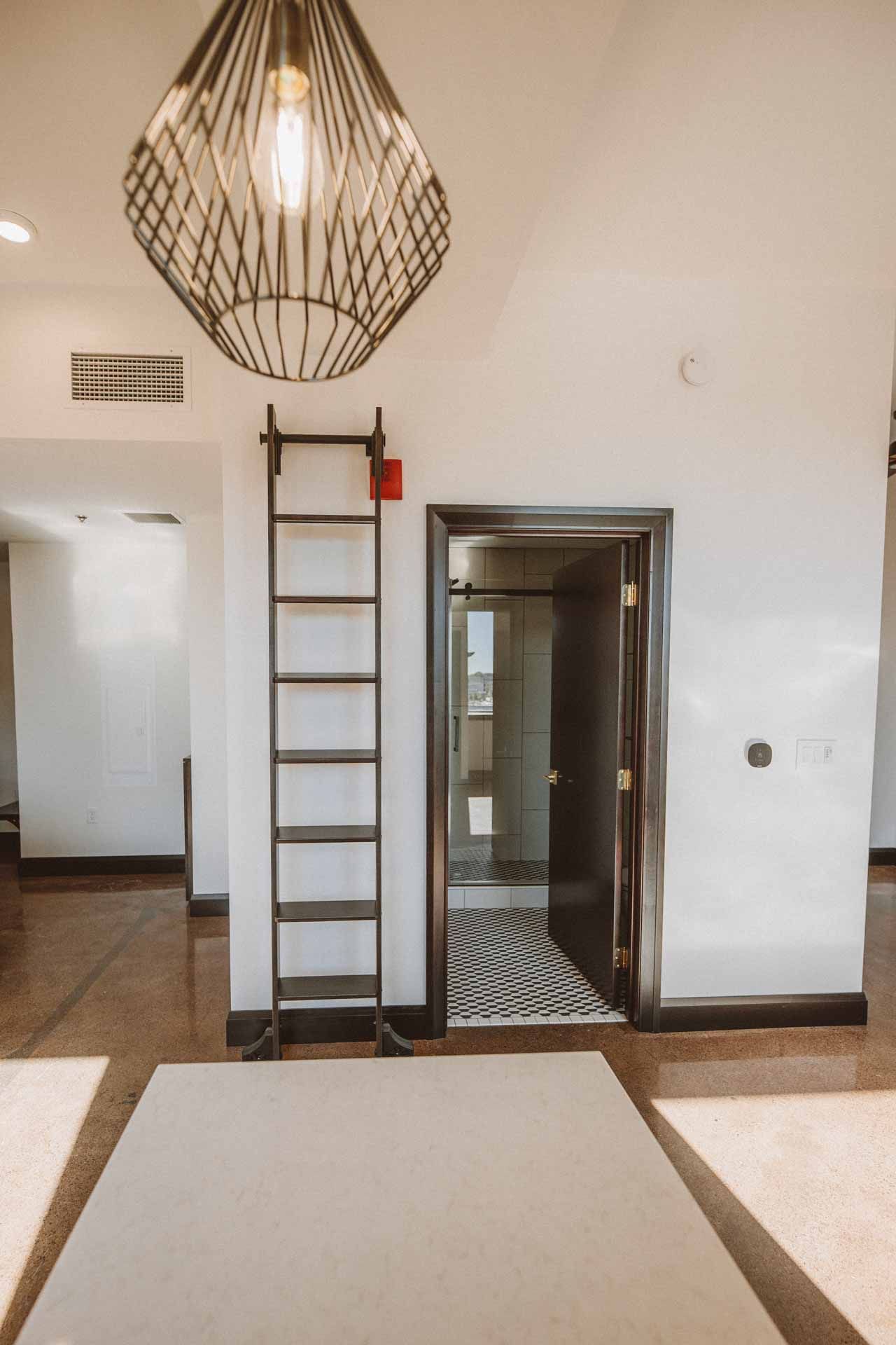 A ladder is hanging from the ceiling in a room next to a door.