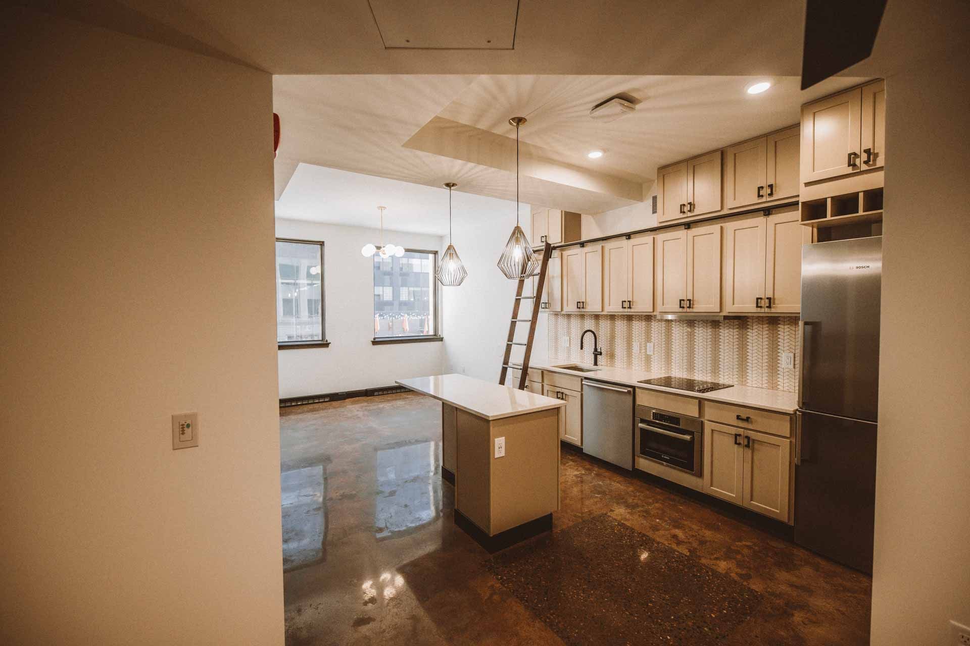 An empty kitchen with stainless steel appliances and wooden cabinets.
