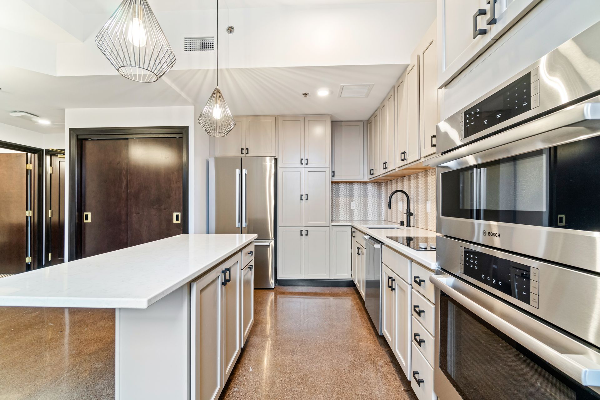 Modern kitchen with stainless steel appliances, white island, and light gray cabinets.