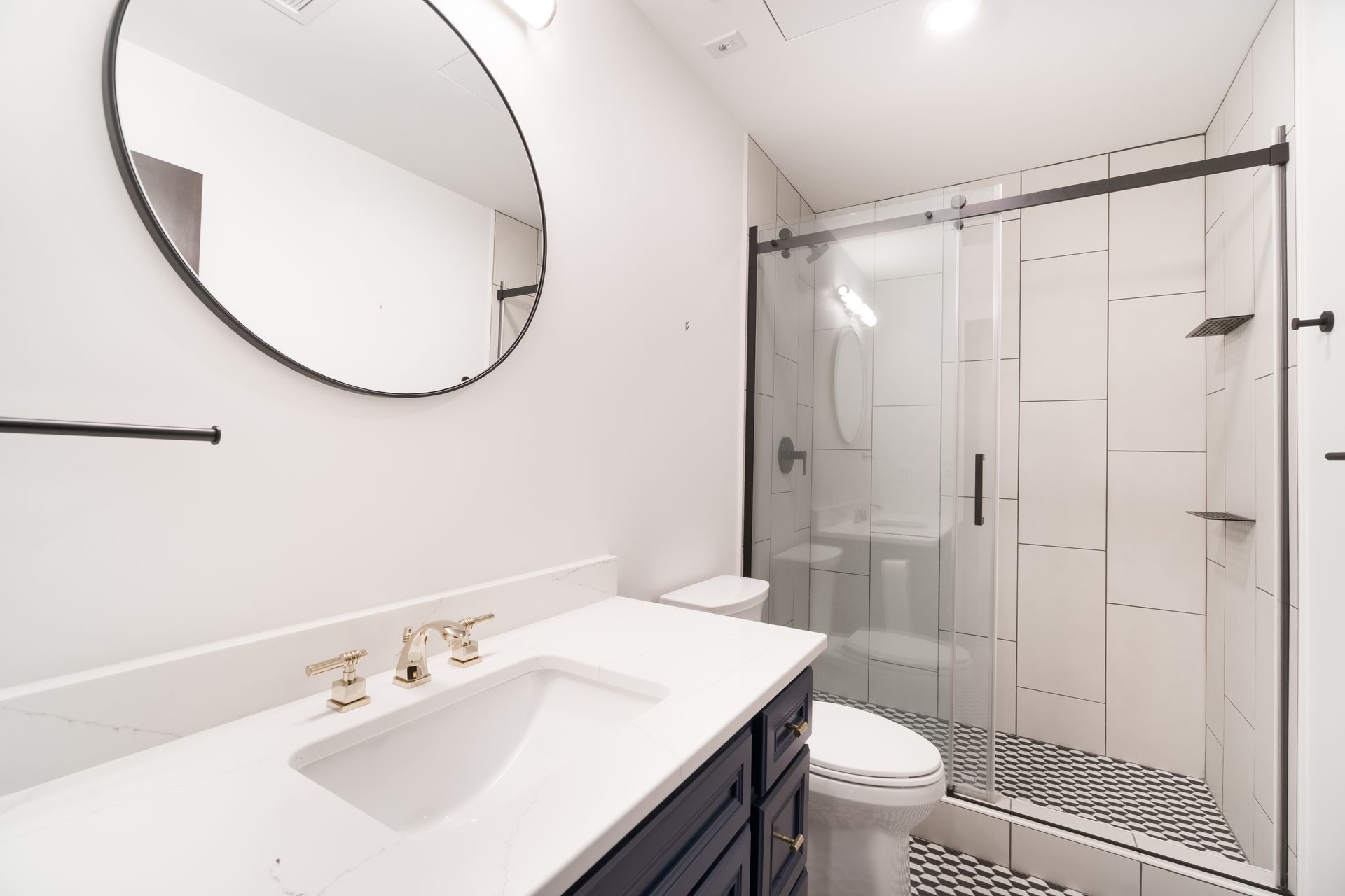 Modern bathroom with a vanity, toilet, shower, and black and white patterned floor.