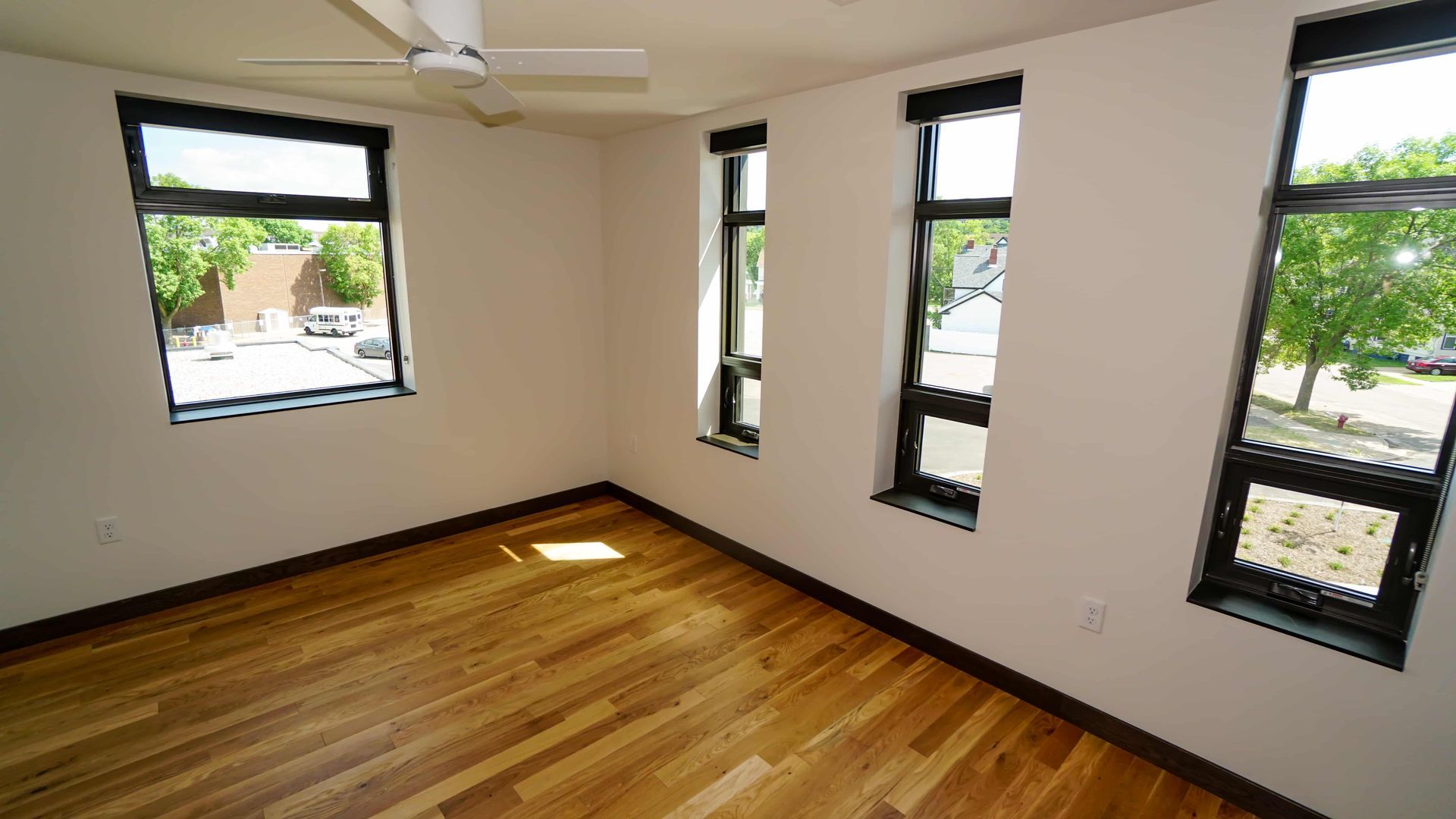 An empty room with hardwood floors and a ceiling fan.
