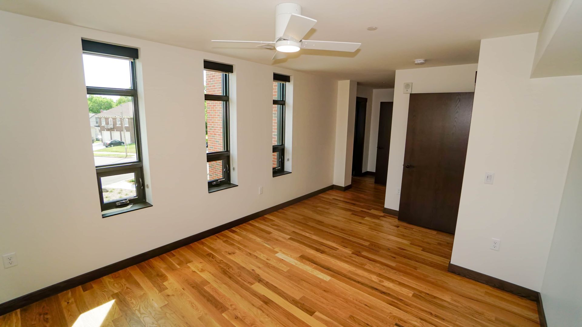 An empty room with hardwood floors and a ceiling fan