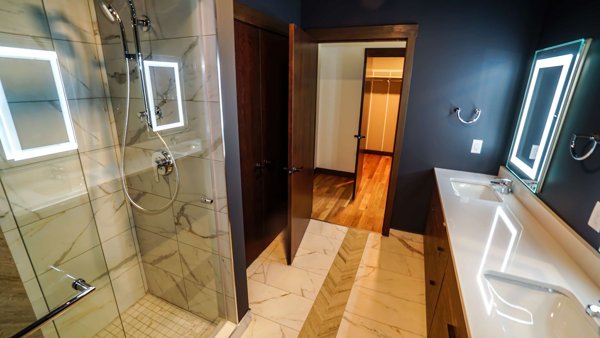 A bathroom with a walk in shower , sink and mirrors.