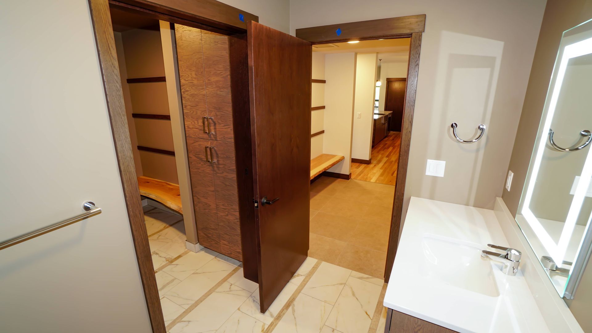 A bathroom with a sink , mirror and walk in closet.