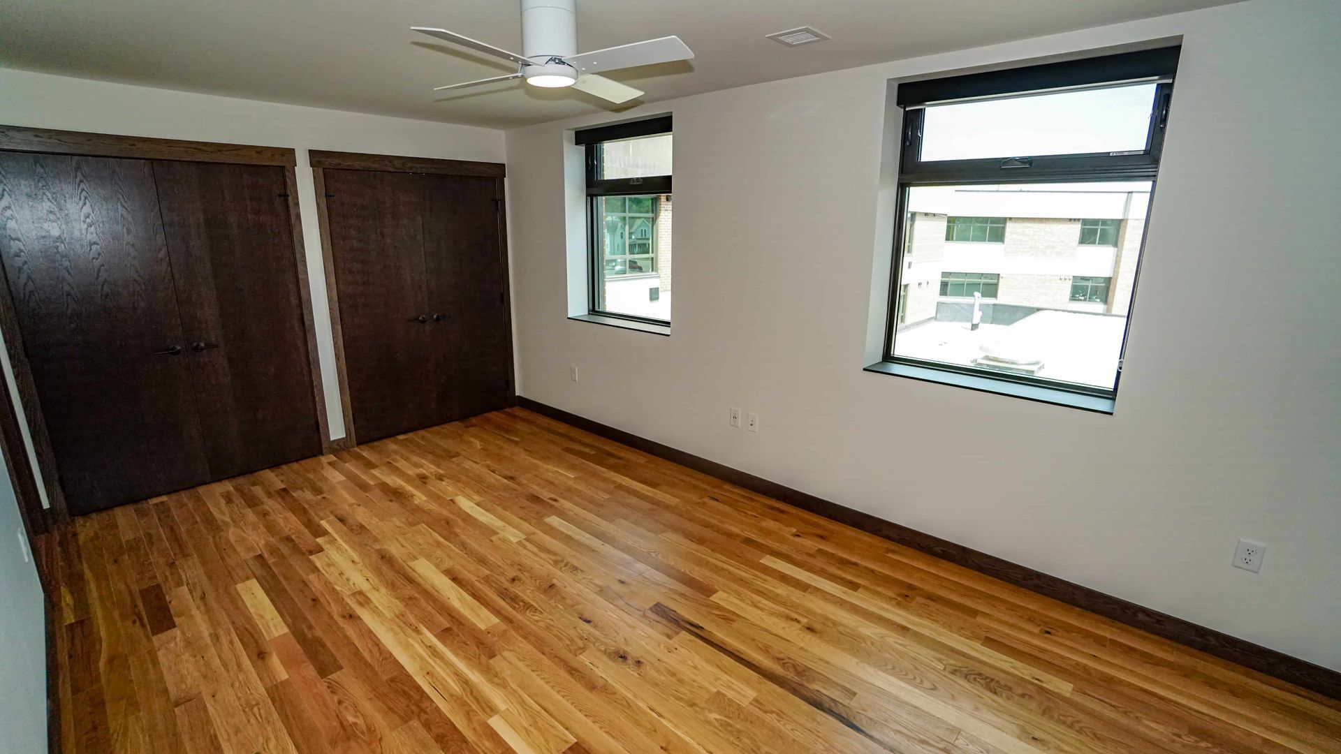 An empty bedroom with hardwood floors and a ceiling fan.