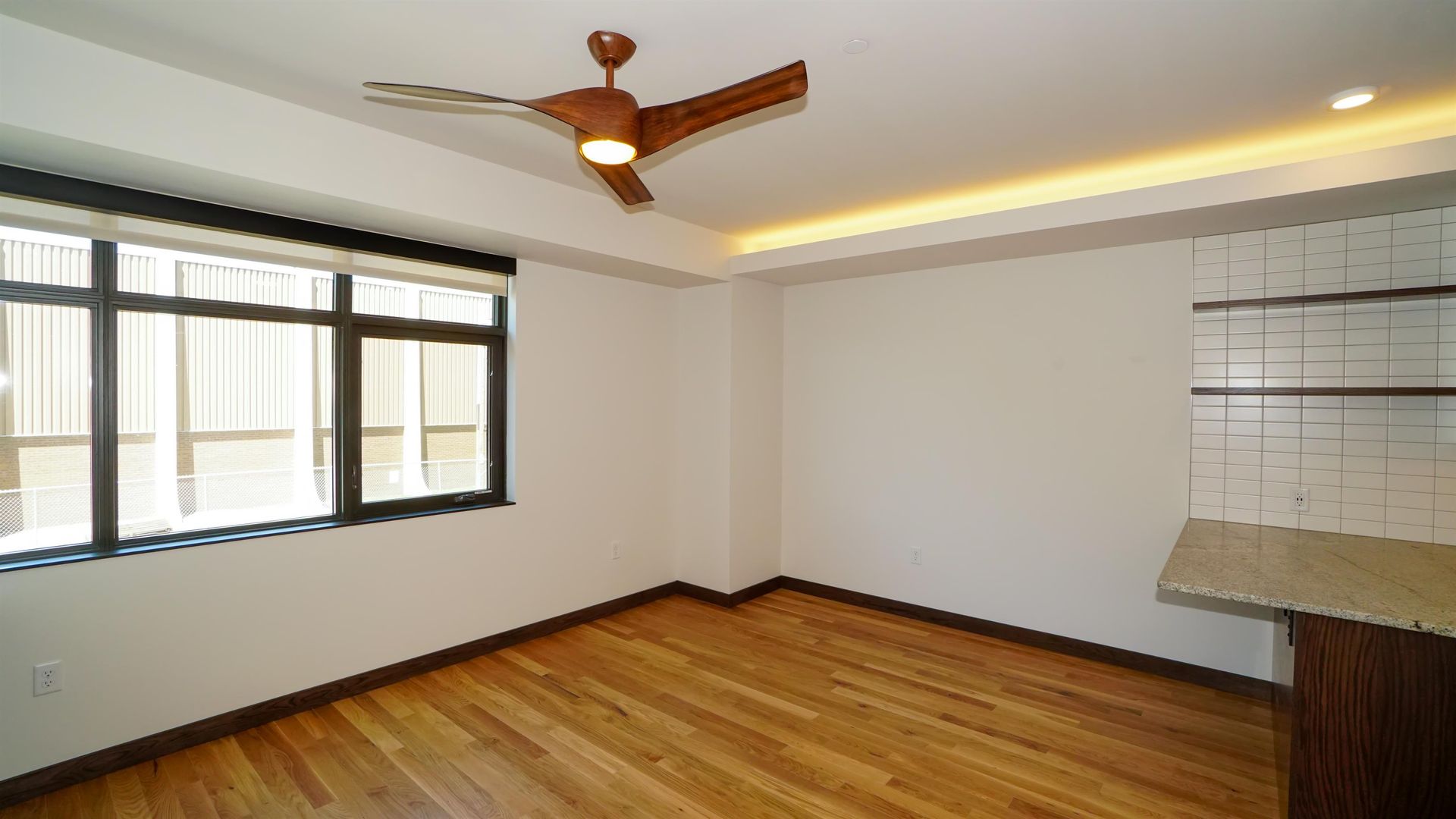 An empty room with hardwood floors and a ceiling fan.