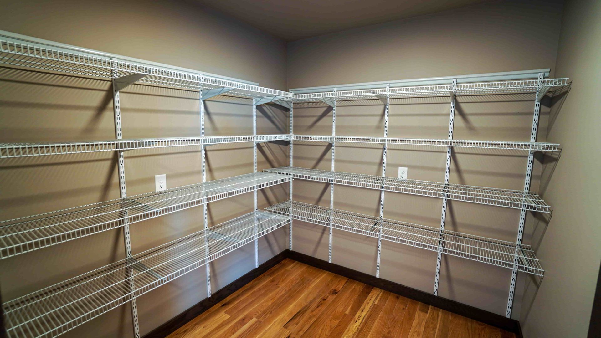 A walk in closet with lots of shelves and wooden floors.