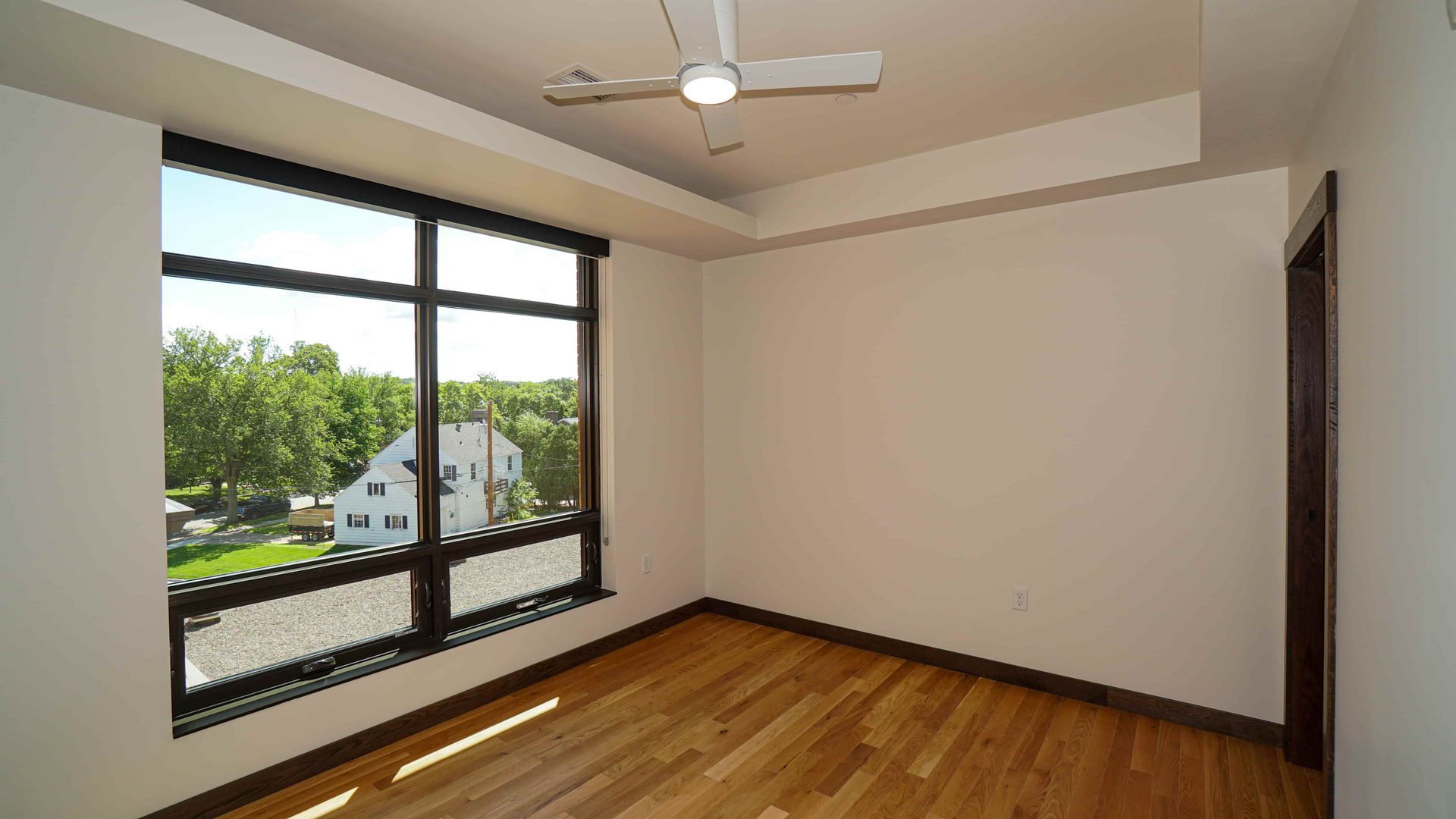 An empty room with hardwood floors and a ceiling fan.