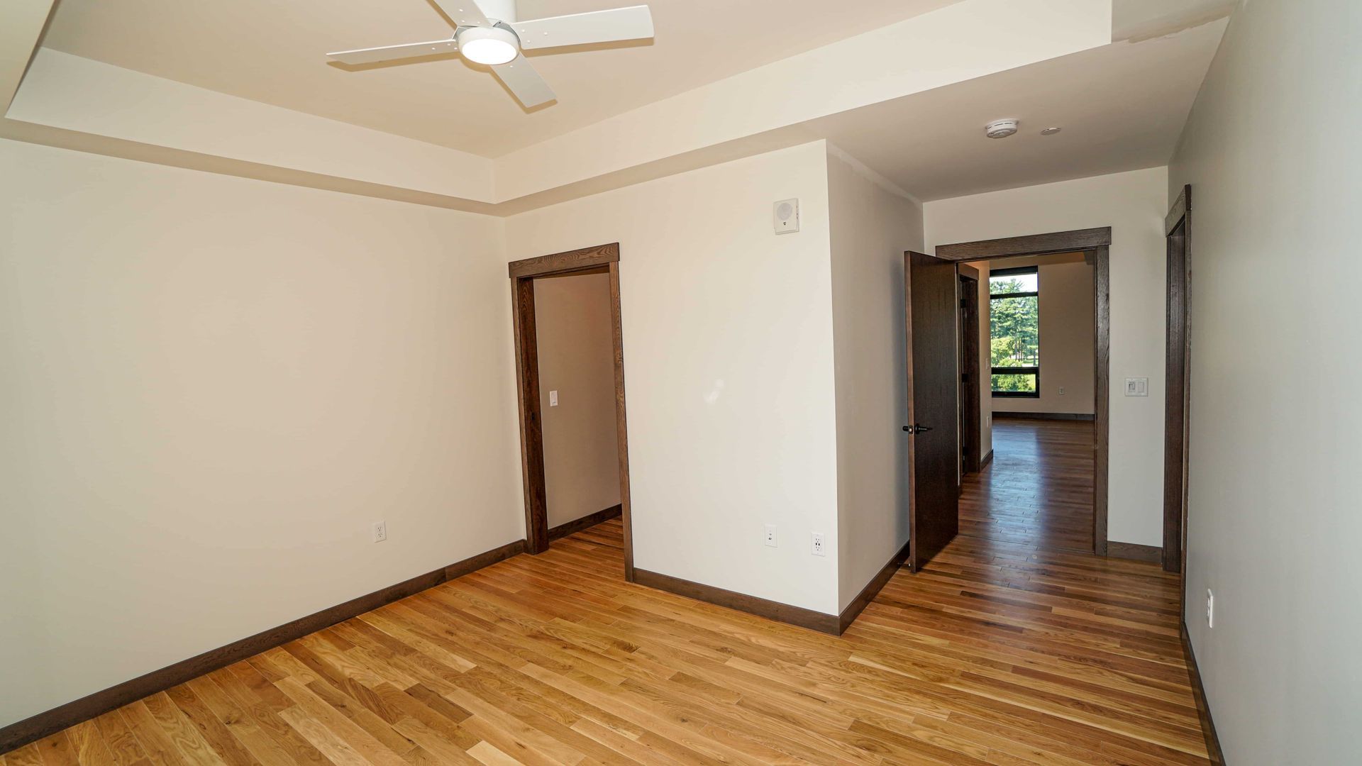 An empty room with hardwood floors and a ceiling fan.