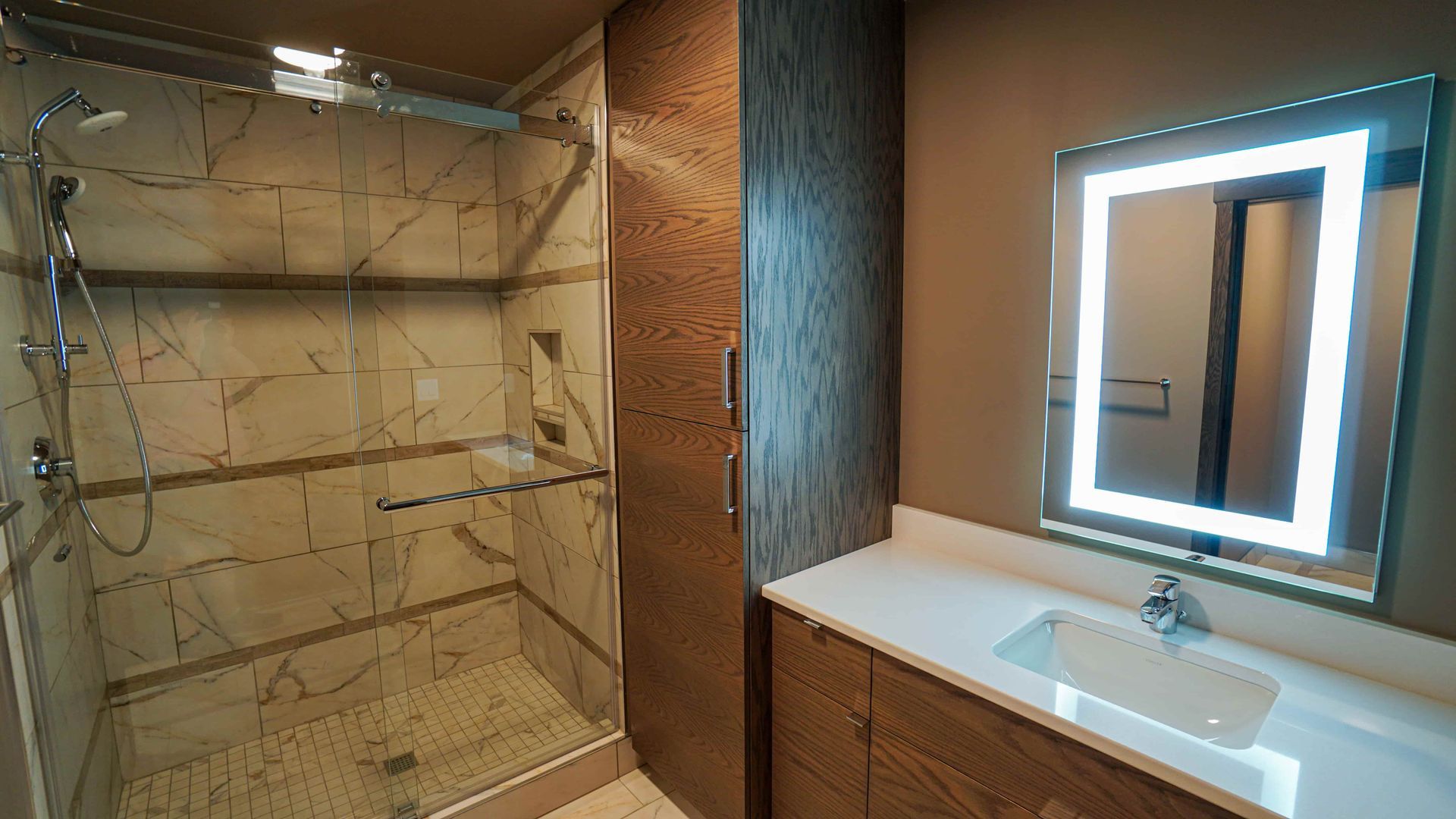 A bathroom with a walk in shower , sink and mirror.