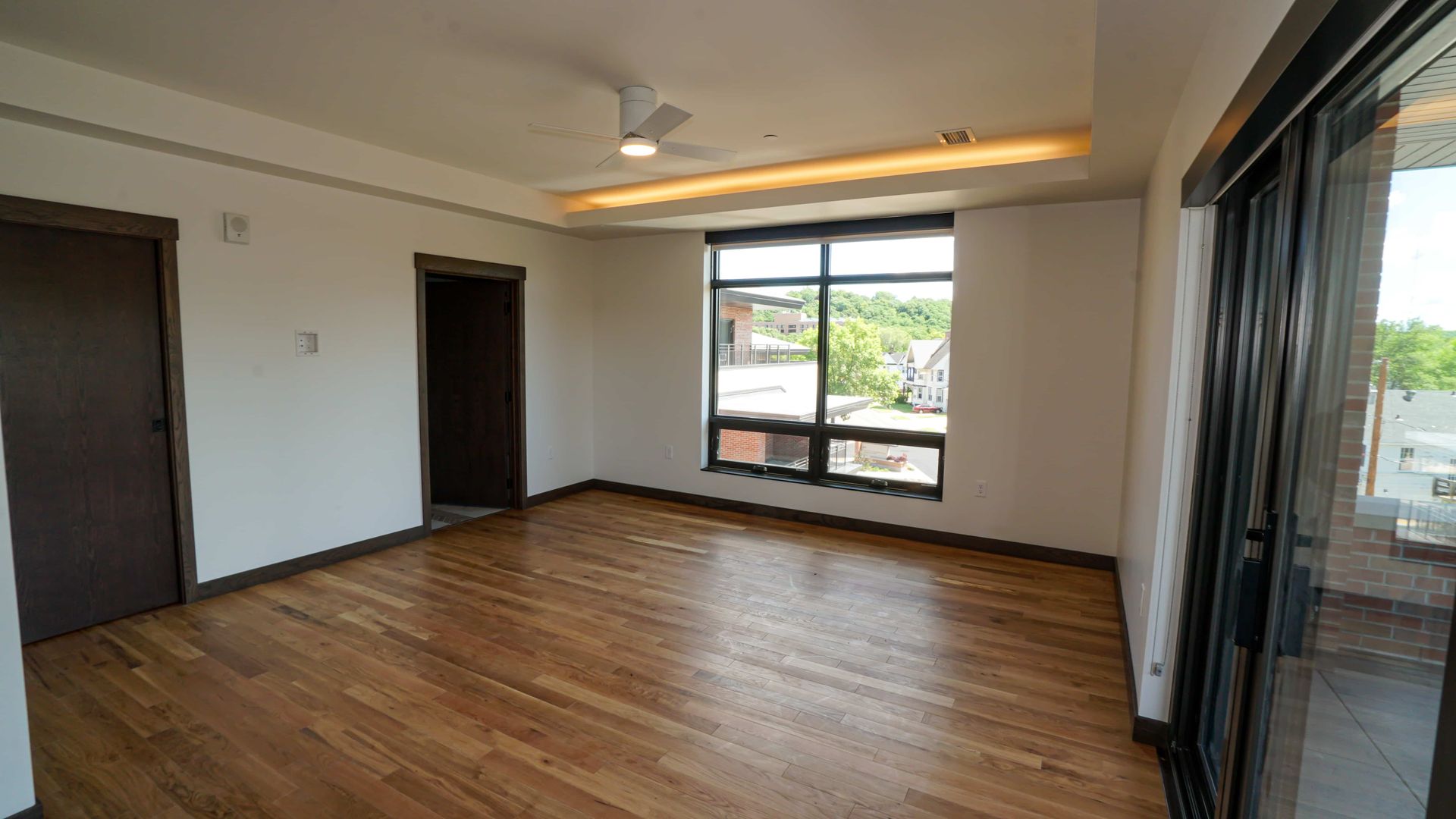 An empty living room with hardwood floors and a ceiling fan.