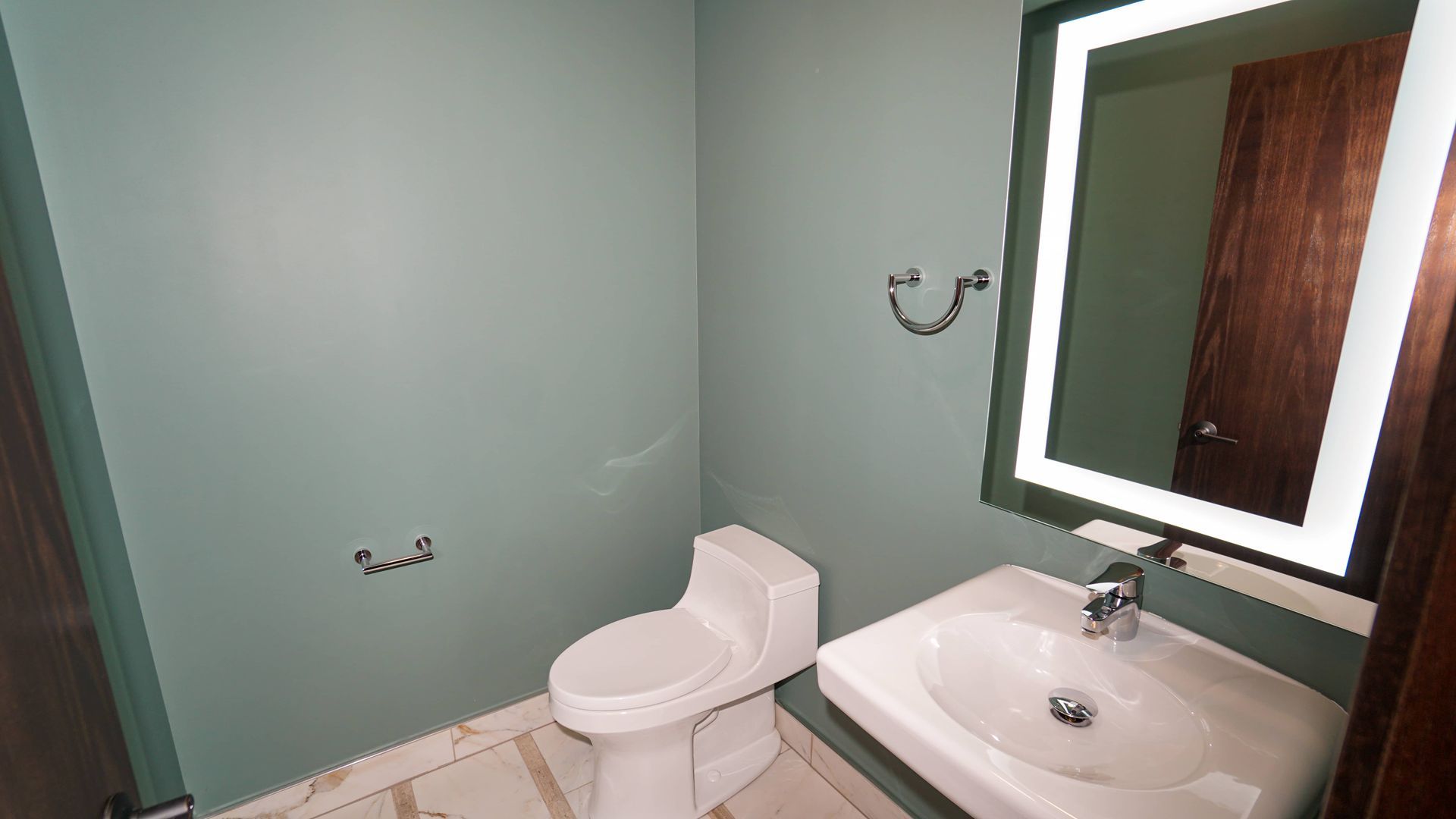 A bathroom with a toilet , sink and mirror.