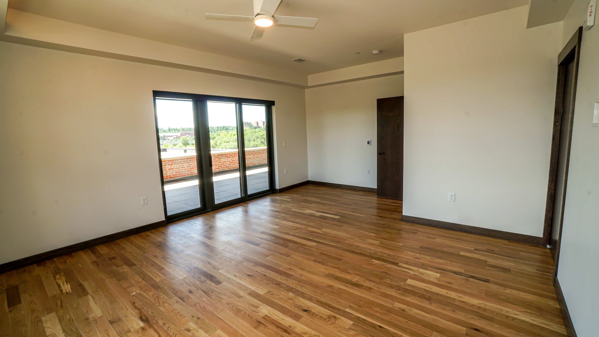 An empty room with hardwood floors and a ceiling fan.