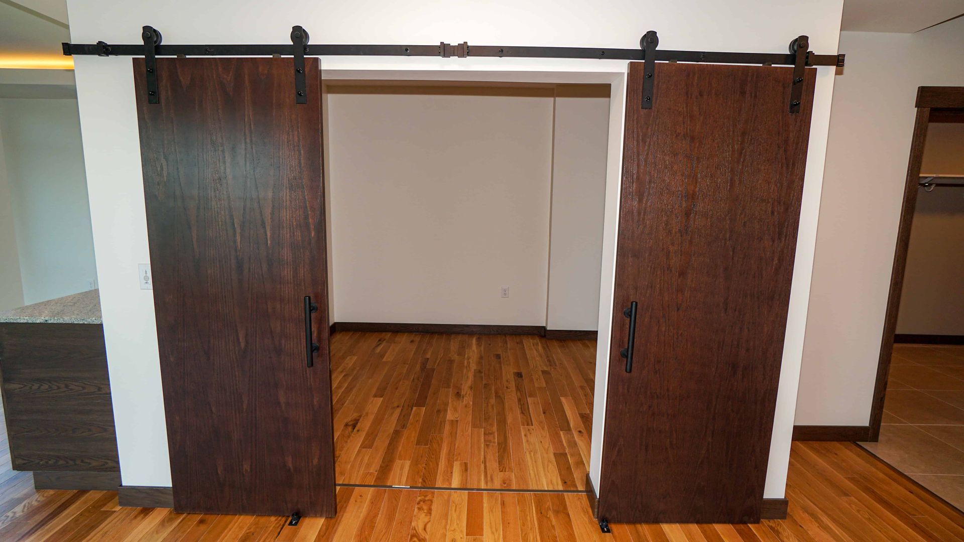 A pair of sliding barn doors in a room with hardwood floors.