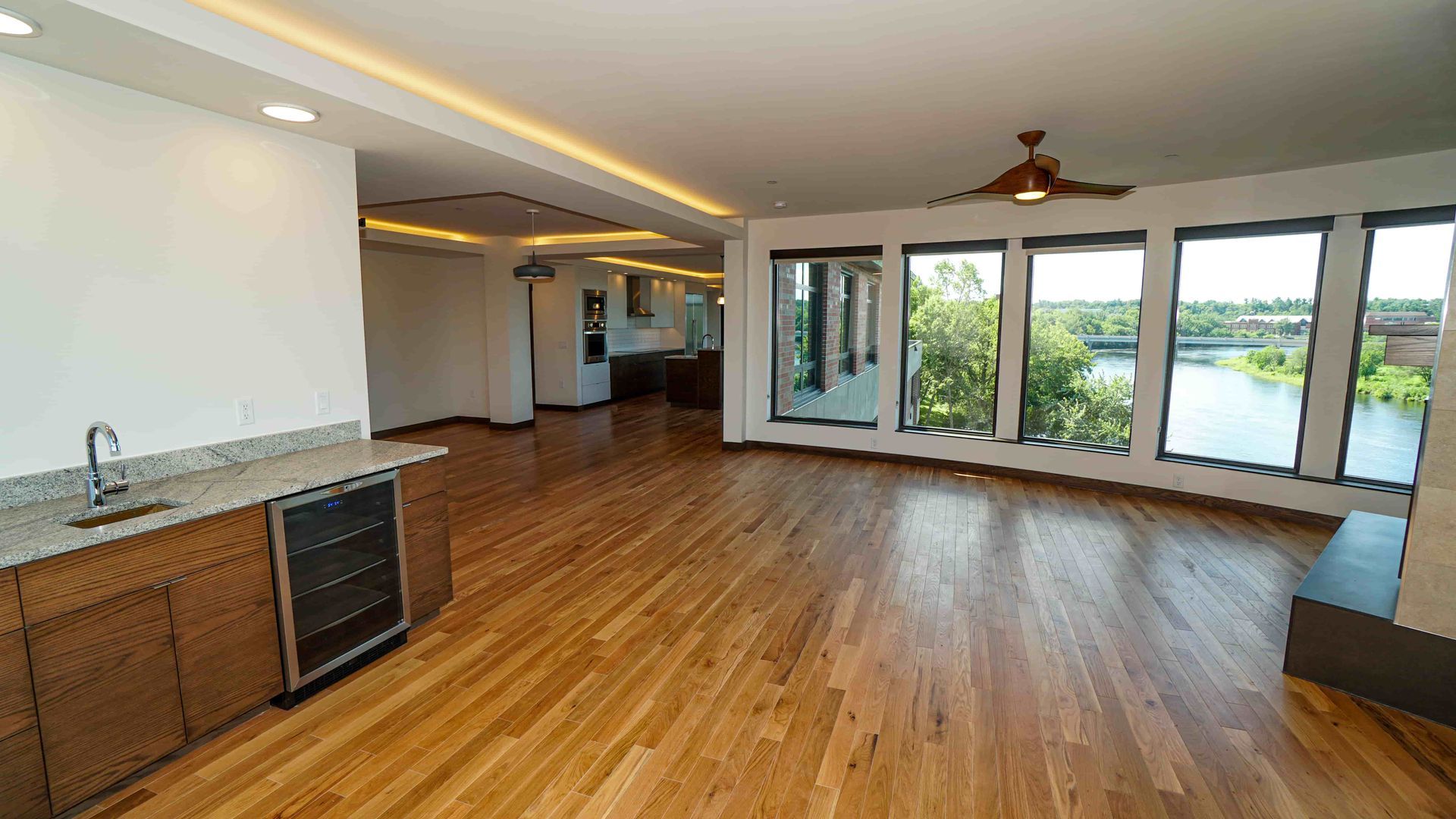A large empty room with hardwood floors and a ceiling fan