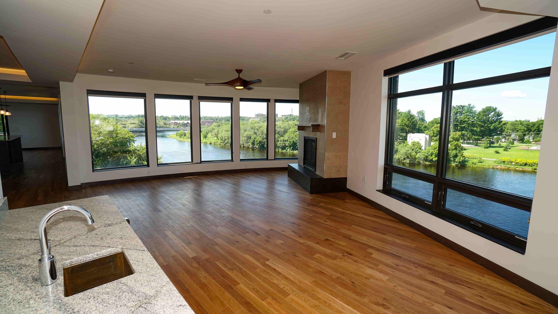 An empty living room with lots of windows and a fireplace