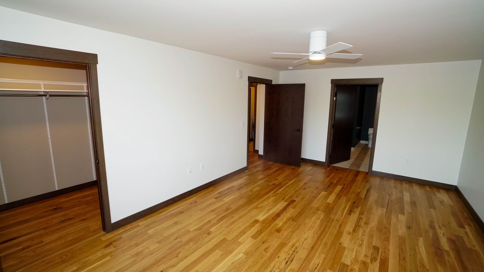An empty living room with hardwood floors and a ceiling fan.