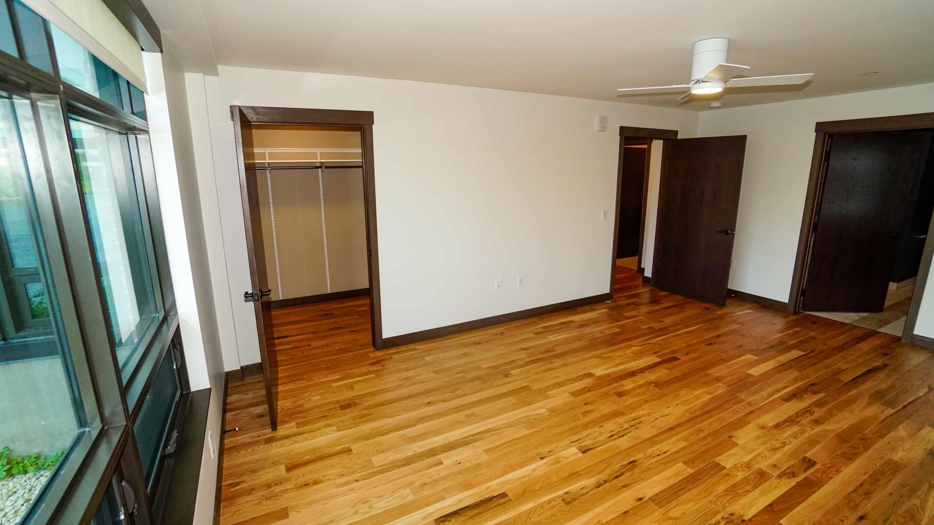 An empty room with hardwood floors and a ceiling fan.