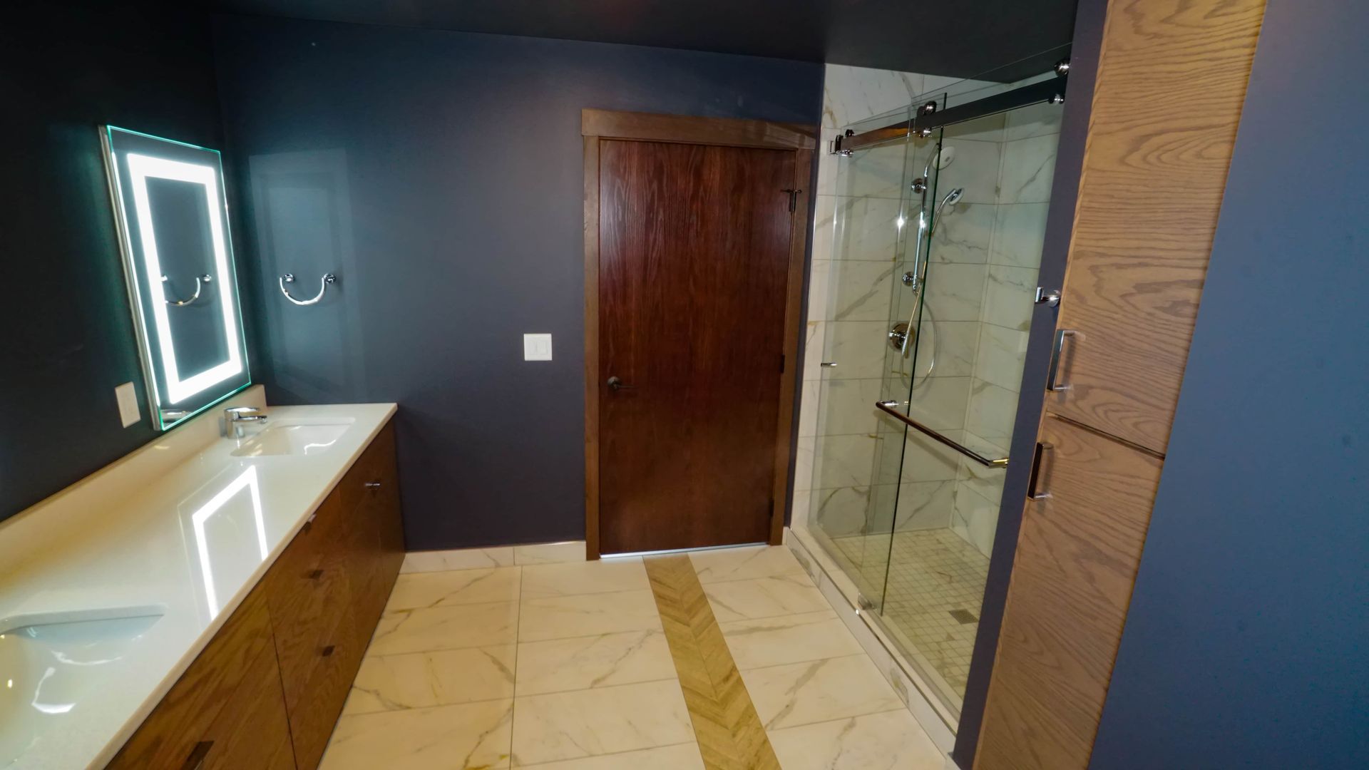 A bathroom with a walk in shower , sink and mirror.