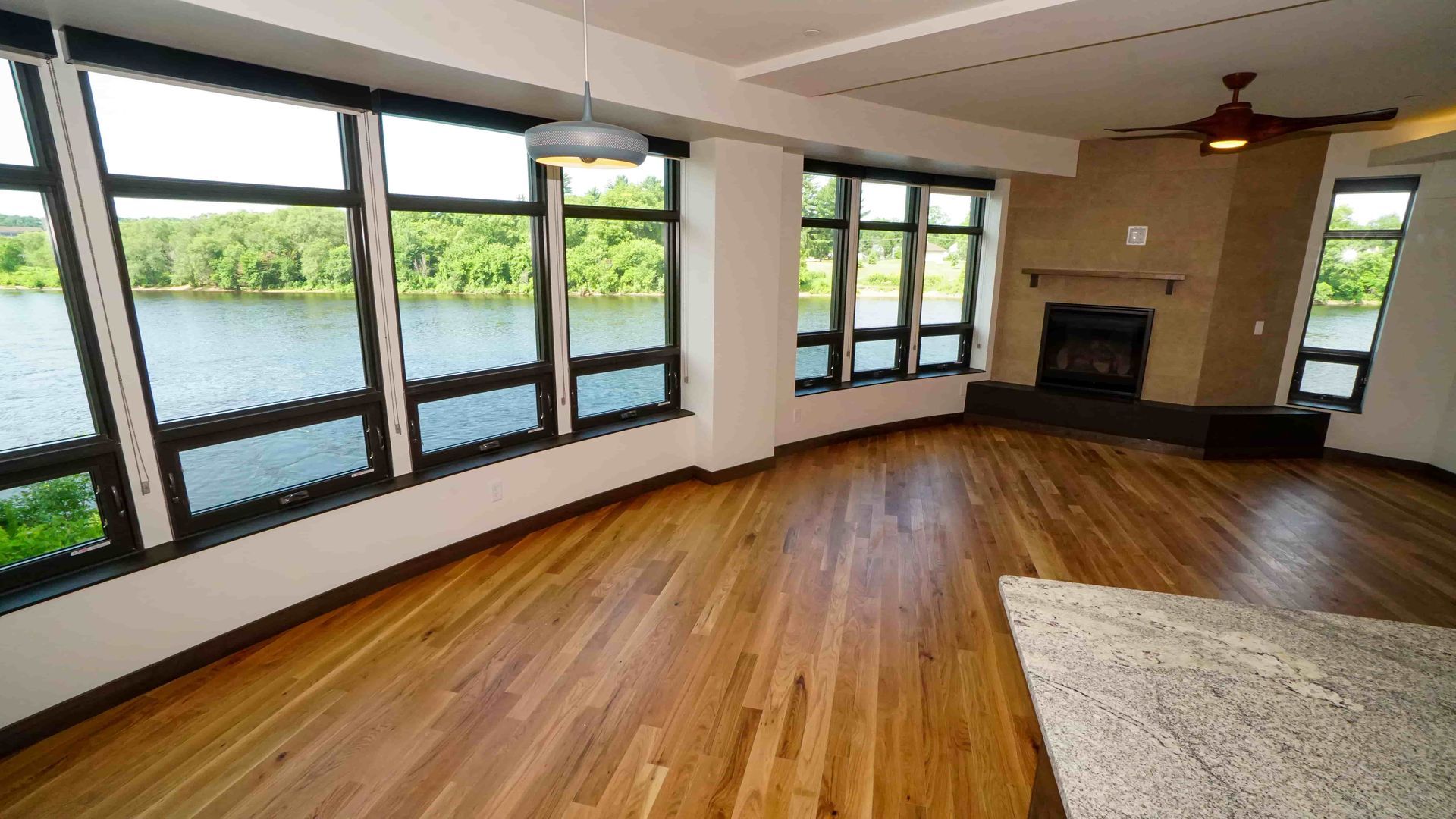 An empty living room with a fireplace and lots of windows