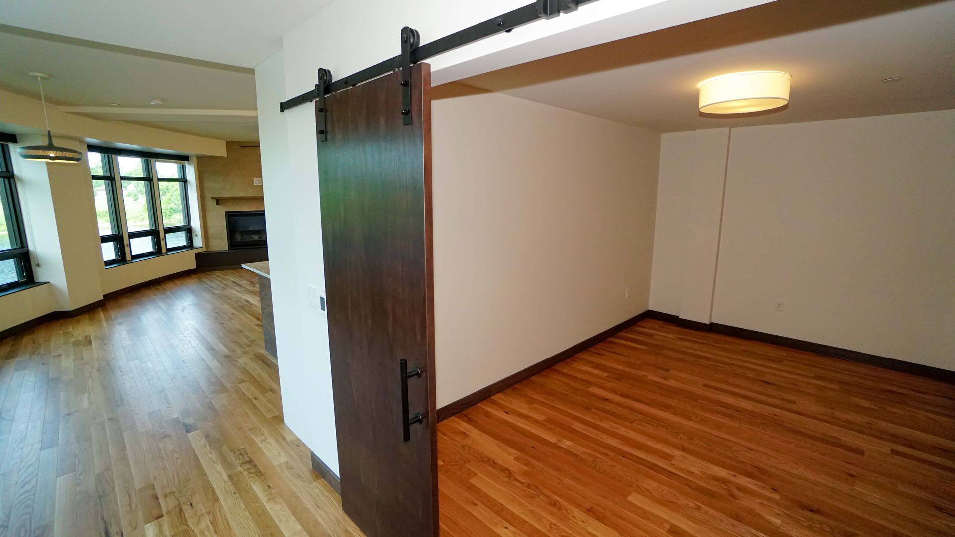 An empty room with hardwood floors and a sliding barn door.