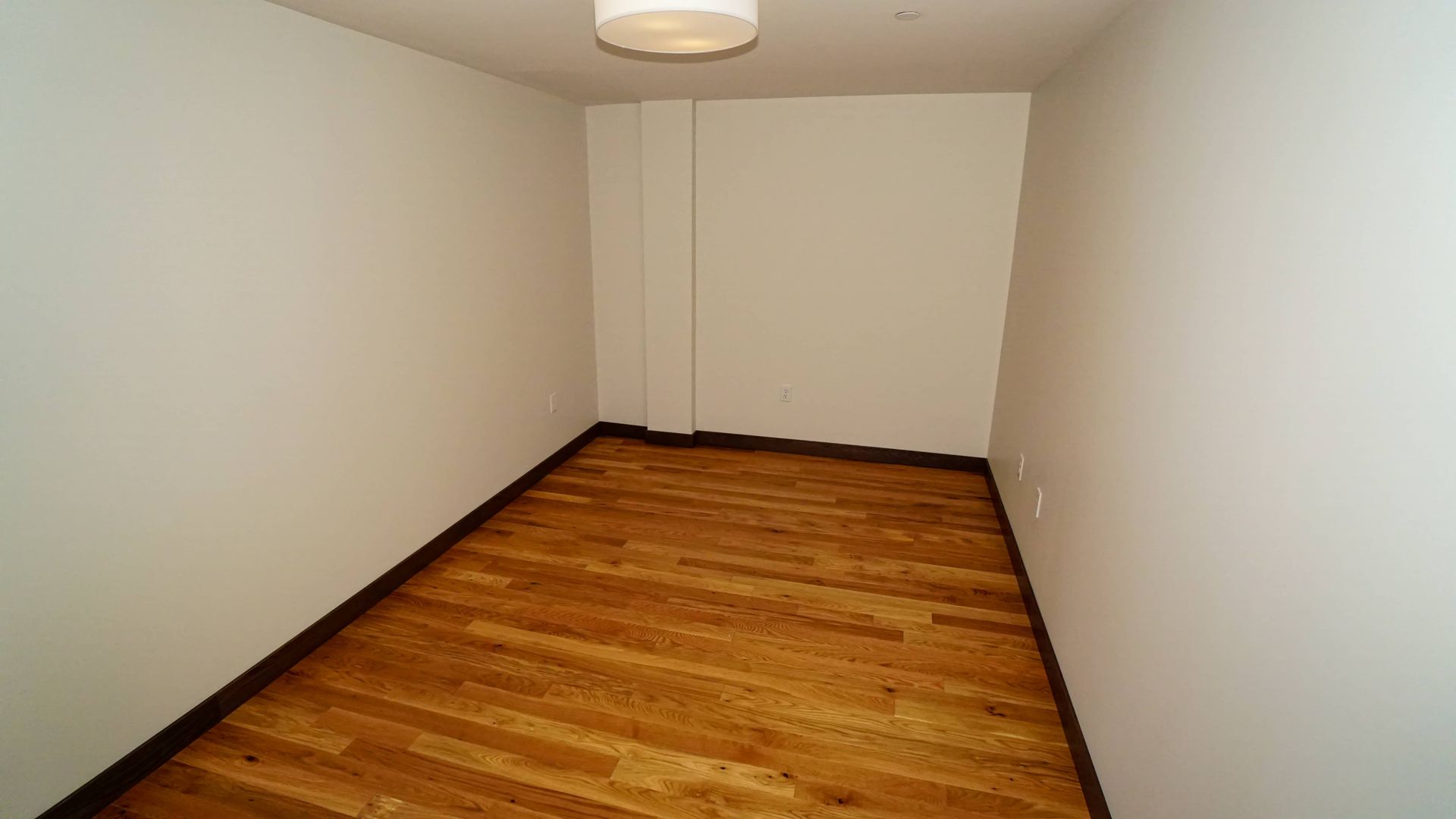 An empty room with hardwood floors and white walls.
