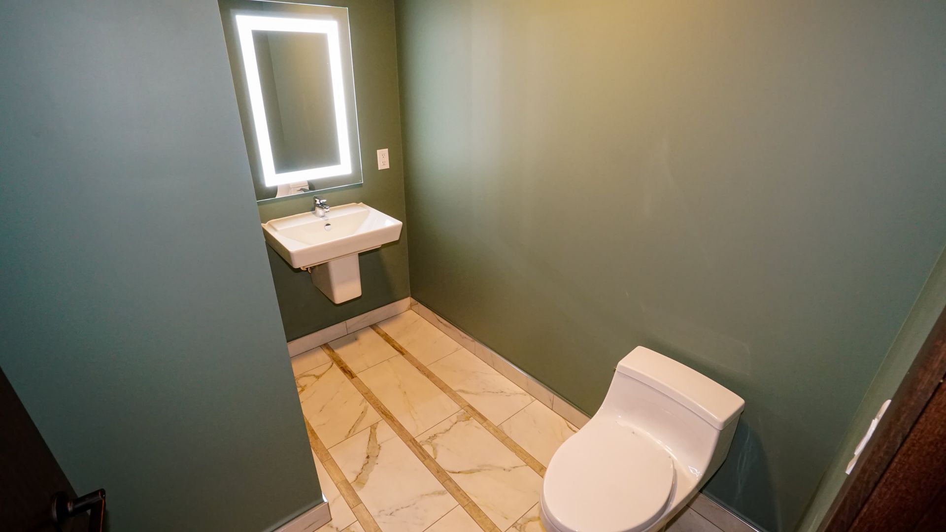 A bathroom with a toilet , sink and mirror.