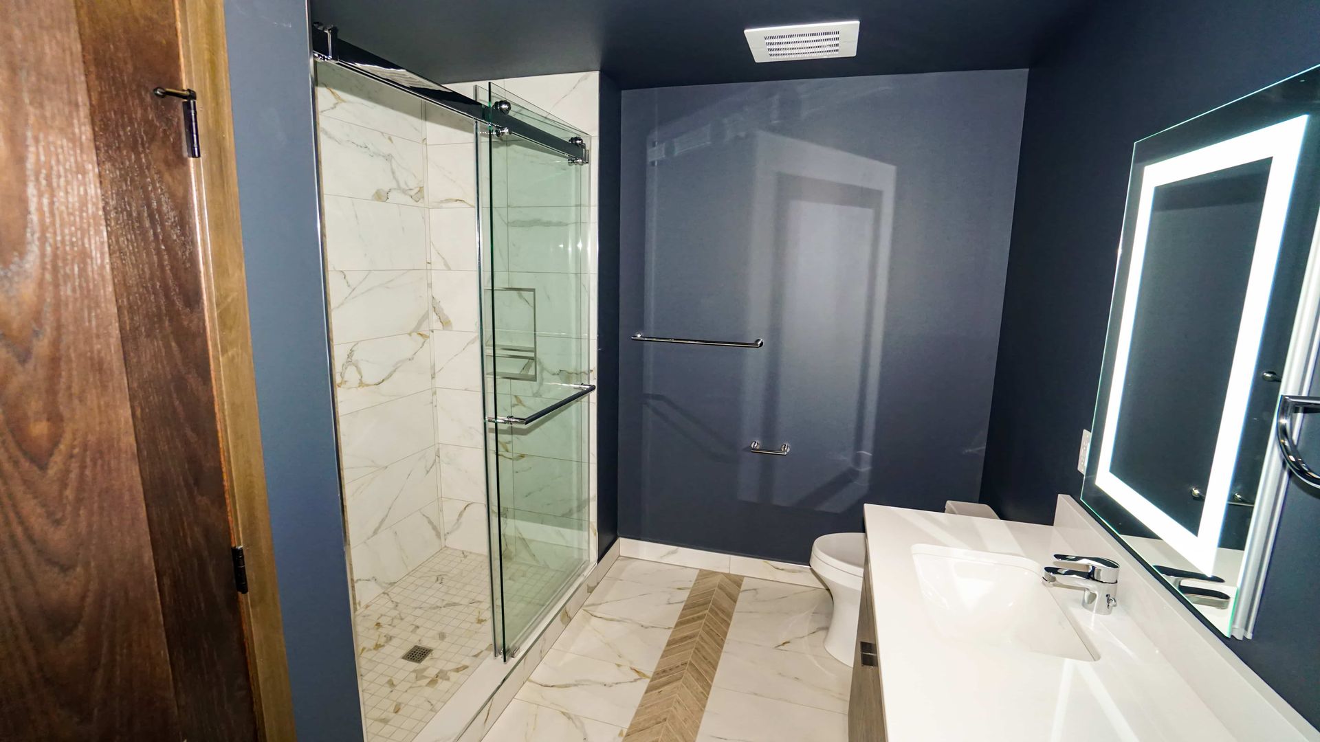 A bathroom with a sink , toilet , shower and mirror.