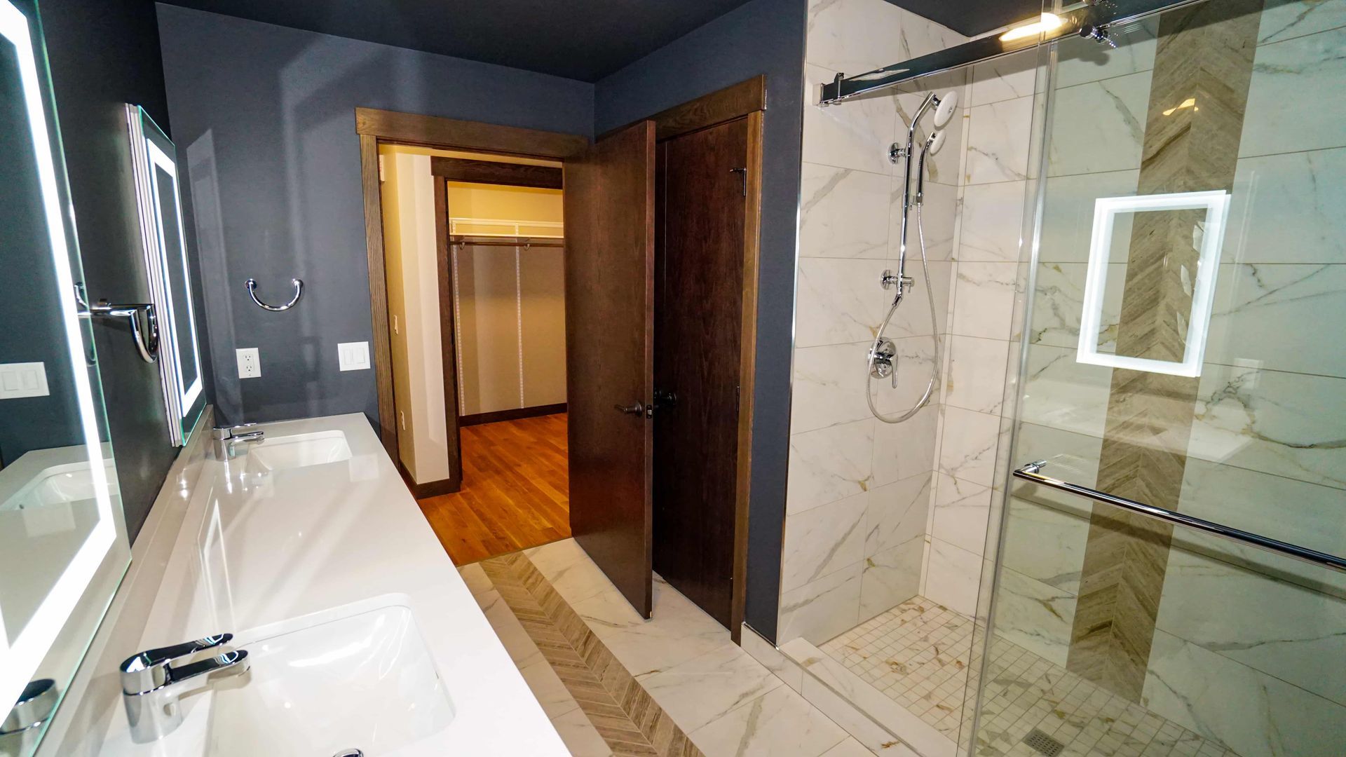 A bathroom with a walk in shower , sink and mirror.