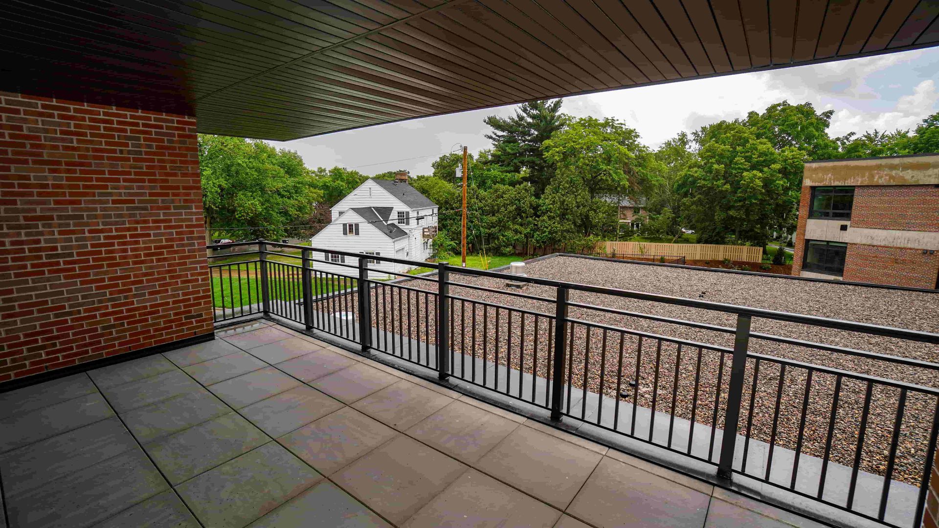 A balcony with a railing and a view of a house and trees.