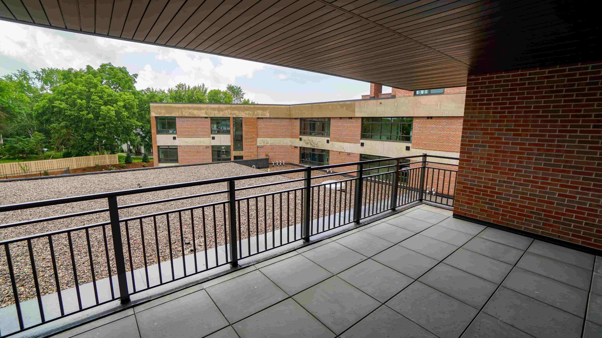 A balcony with a railing and a brick building in the background.