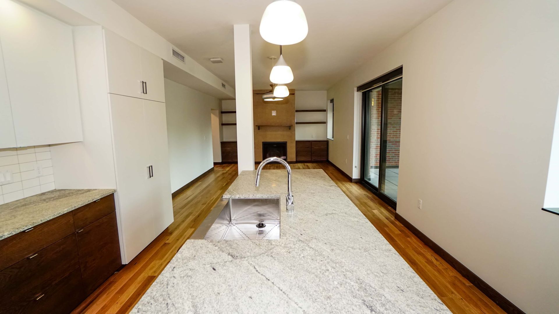 An empty kitchen with granite counter tops and a sink