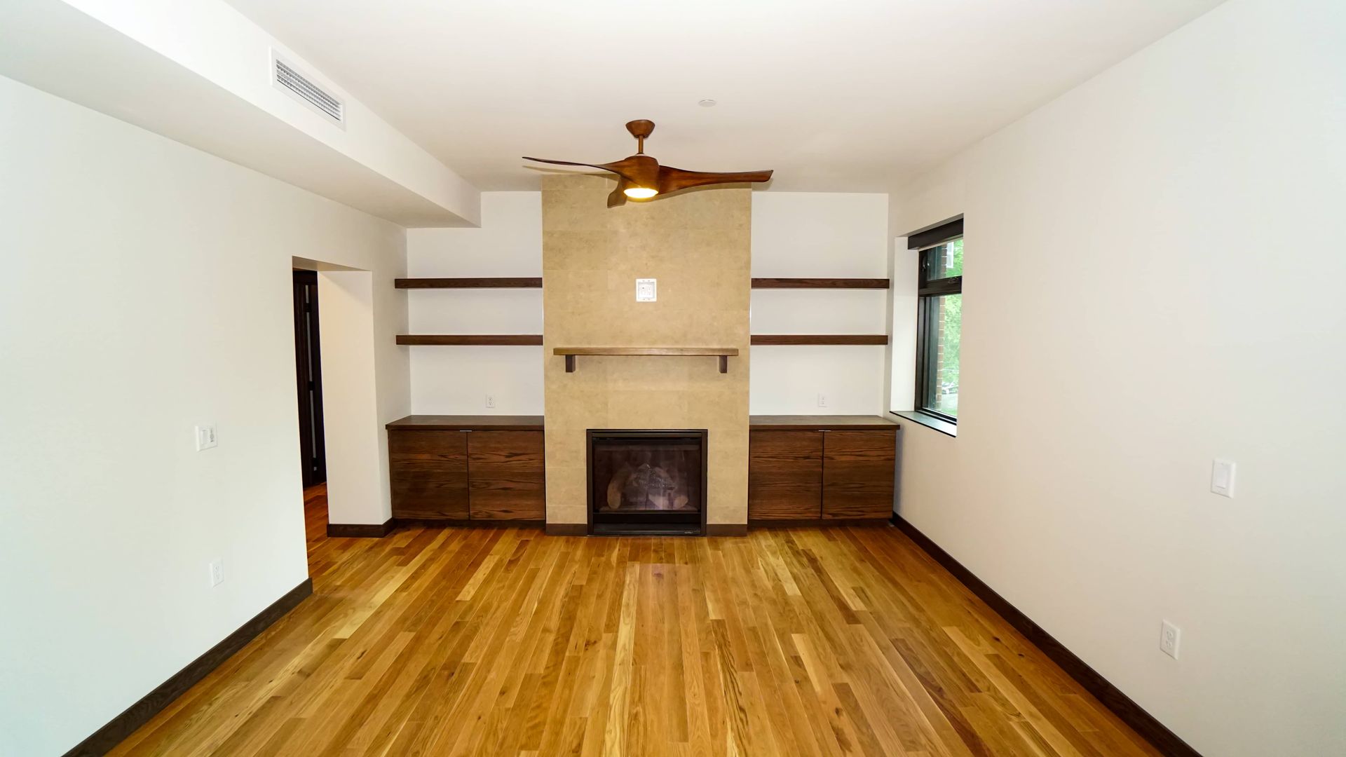 An empty living room with hardwood floors and a fireplace