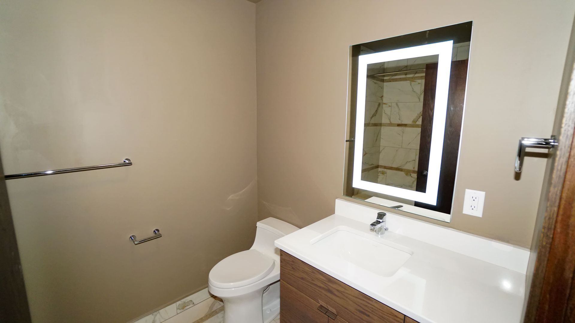 A bathroom with a toilet , sink and mirror.
